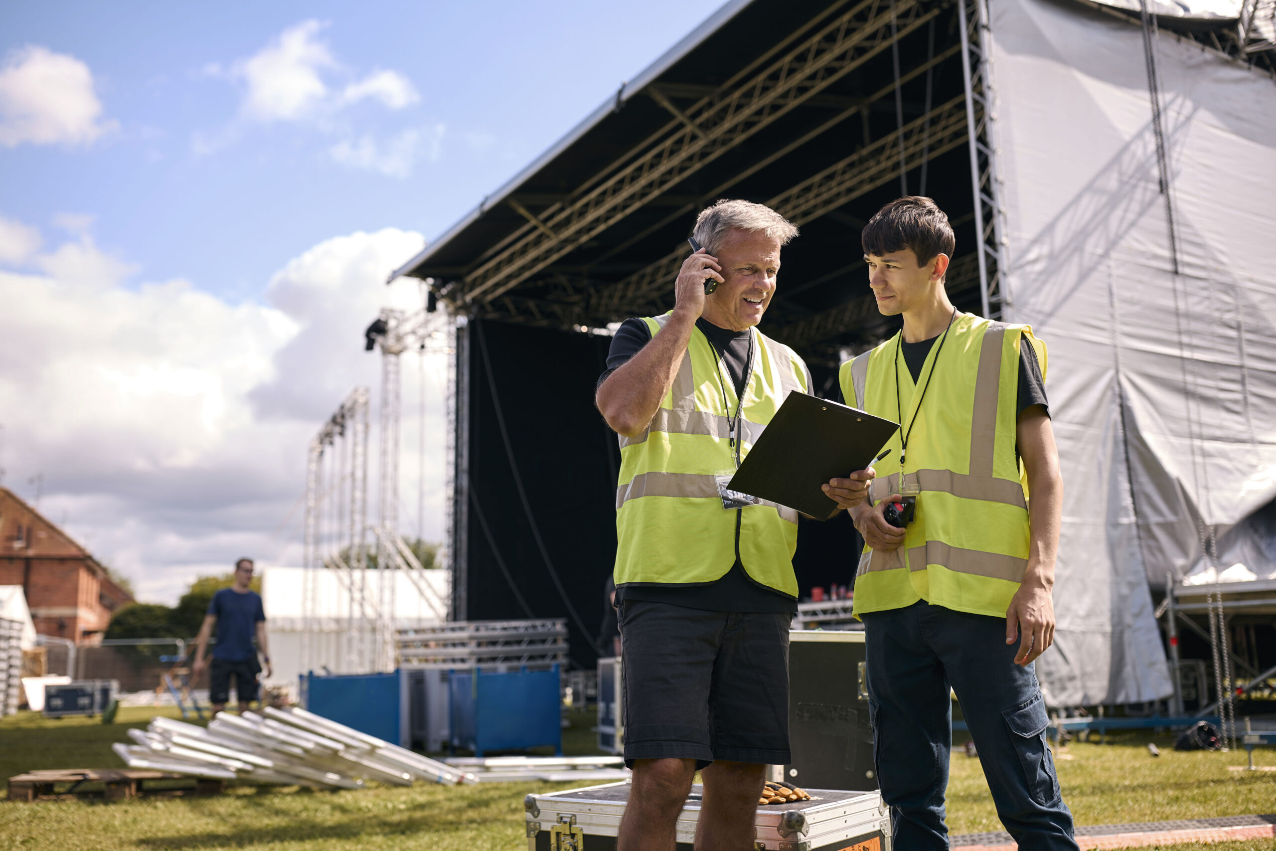 Production Team Talking On Radios And Setting Up Outdoor Stage F